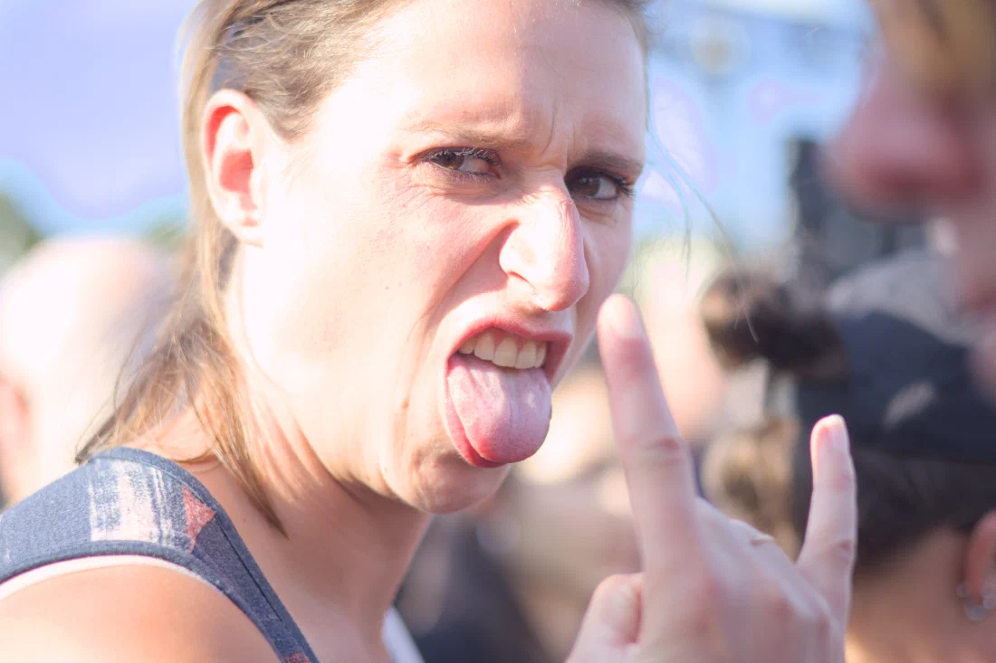 Festival-goer sticking out her tongue and throwing devil-horns, Binic Folk Blues Festival 2025