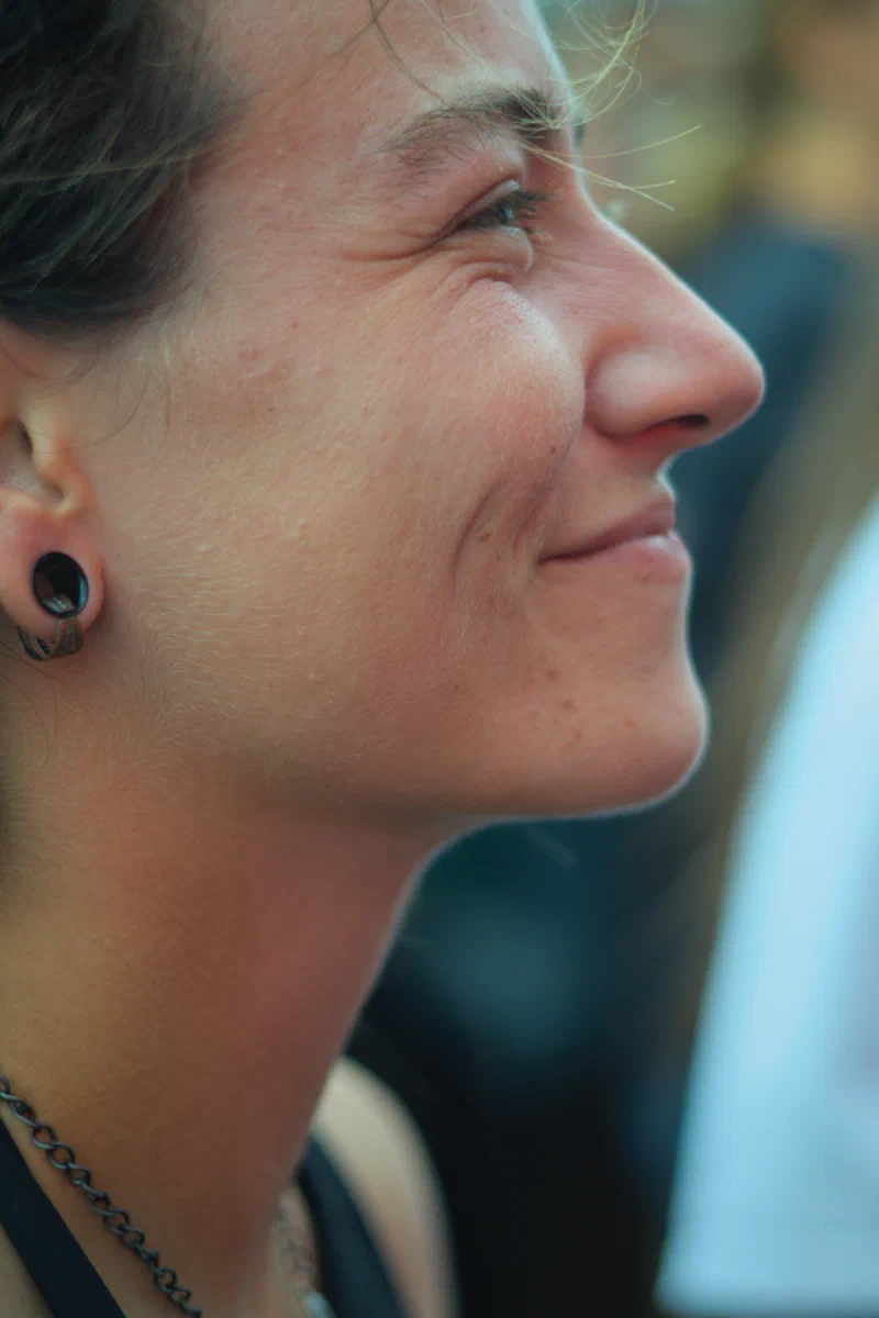 Close profile of a smiling woman with laugh lines and a black ear plug, Binic Folk Blues Festival 2025
