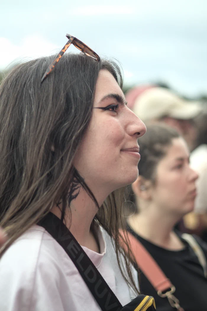 Young woman in profile, sunglasses pushed up on her head, watching the stage in the crowd, Binic Folk Blues Festival 2025
