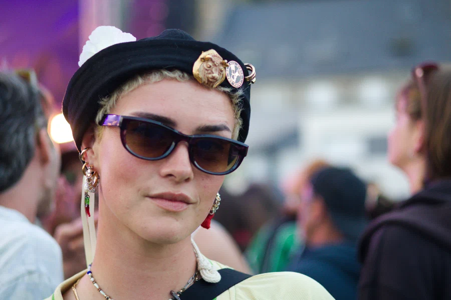 Woman in a black beret with badges and cat-eye sunglasses looking straight into the lens, Binic Folk Blues Festival 2026