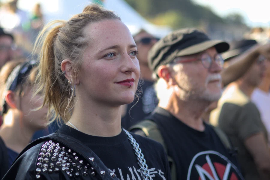 Young punk in a studded leather jacket with a lip ring, backlit at golden hour, Binic Folk Blues Festival 2025